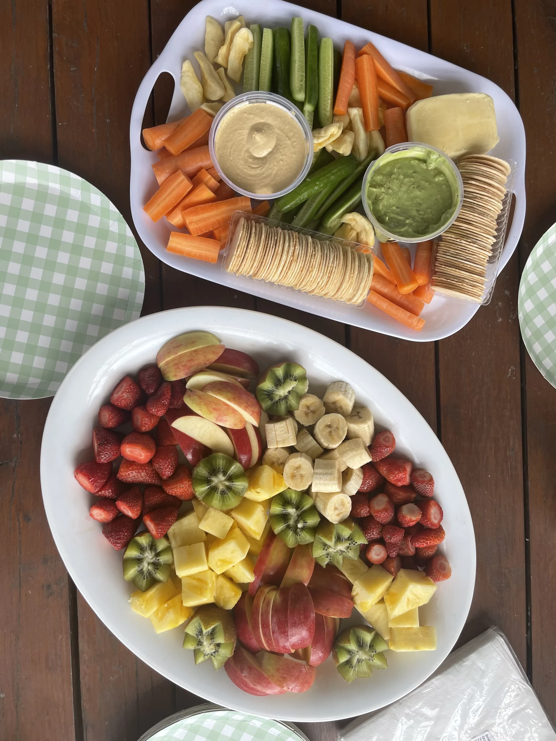 Veggie platter with dips and crackers, plus a colorful fruit platter with apples, bananas, kiwi, strawberries, and pineapple